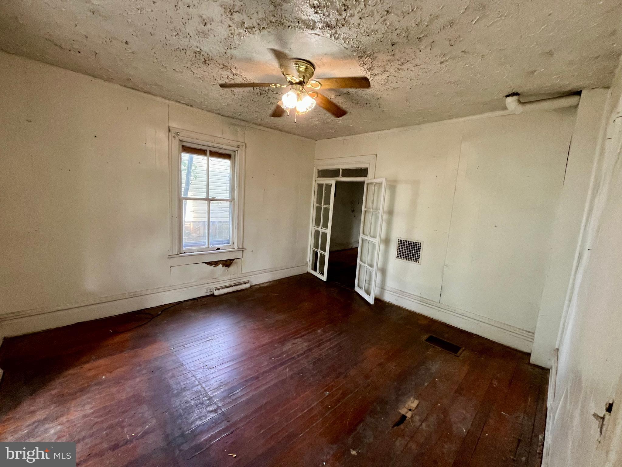 407 Carruthers Street Lexington, VA 24450 - Photo 4 of 29 an empty room with wooden floor chandelier fan and windows