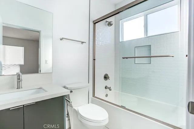 a bathroom with a bathtub shower sink mirror vanity and toilet