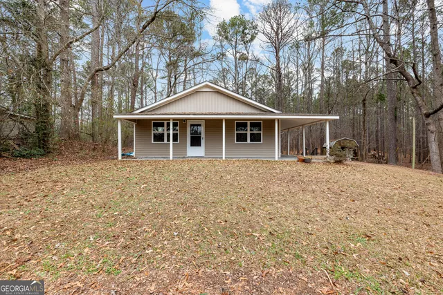 a front view of a house with a yard covered with trees