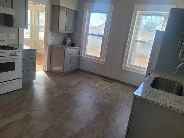 a kitchen with granite countertop a stove a sink and a refrigerator