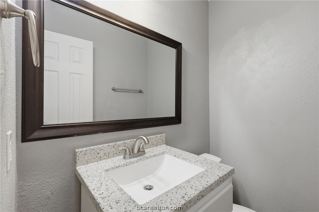 502 West 14th Street Bryan, TX 77803 - Photo 11 of 16 a bathroom with a granite countertop sink and a mirror