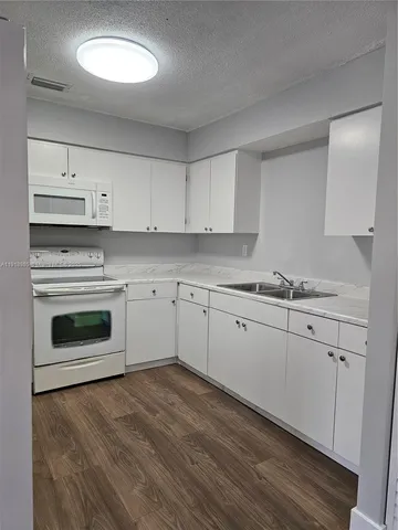 a kitchen with granite countertop white cabinets and white appliances