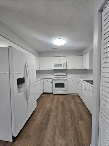 a kitchen with white cabinets and white appliances