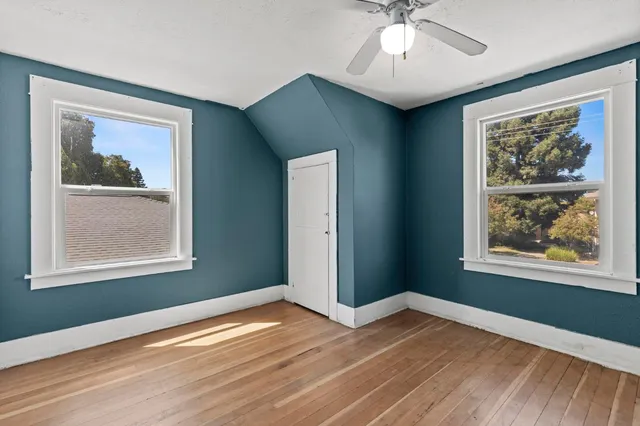 a view of an empty room with window and wooden floor
