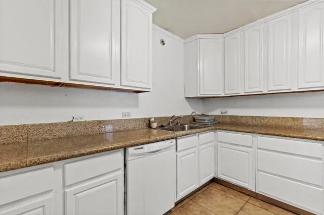 a kitchen with granite countertop white cabinets and a sink