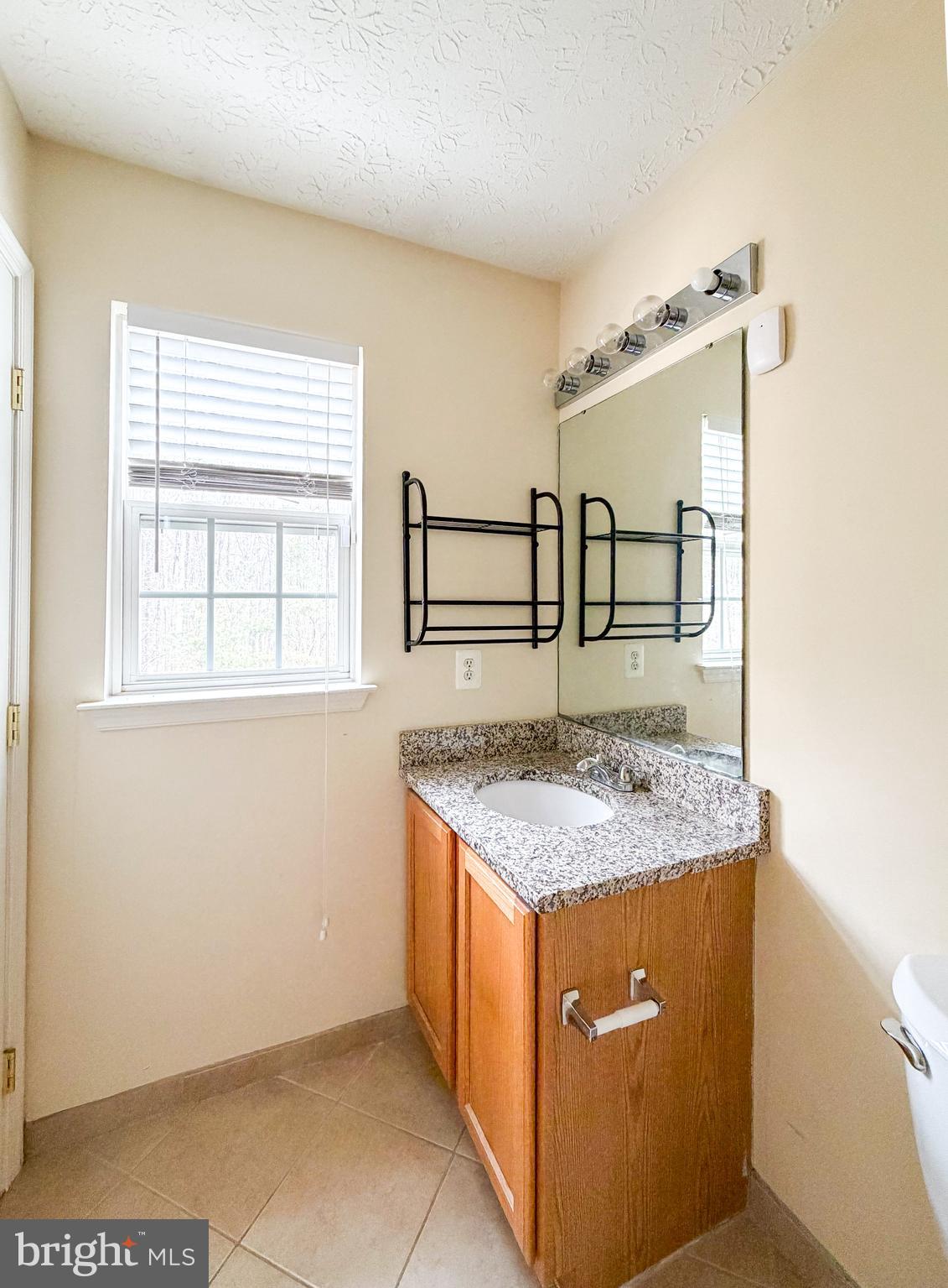 9708 Redwing Drive, Unit 9708 Perry Hall, MD 21128 - Photo 31 of 40 a bathroom with a granite countertop sink and a mirror