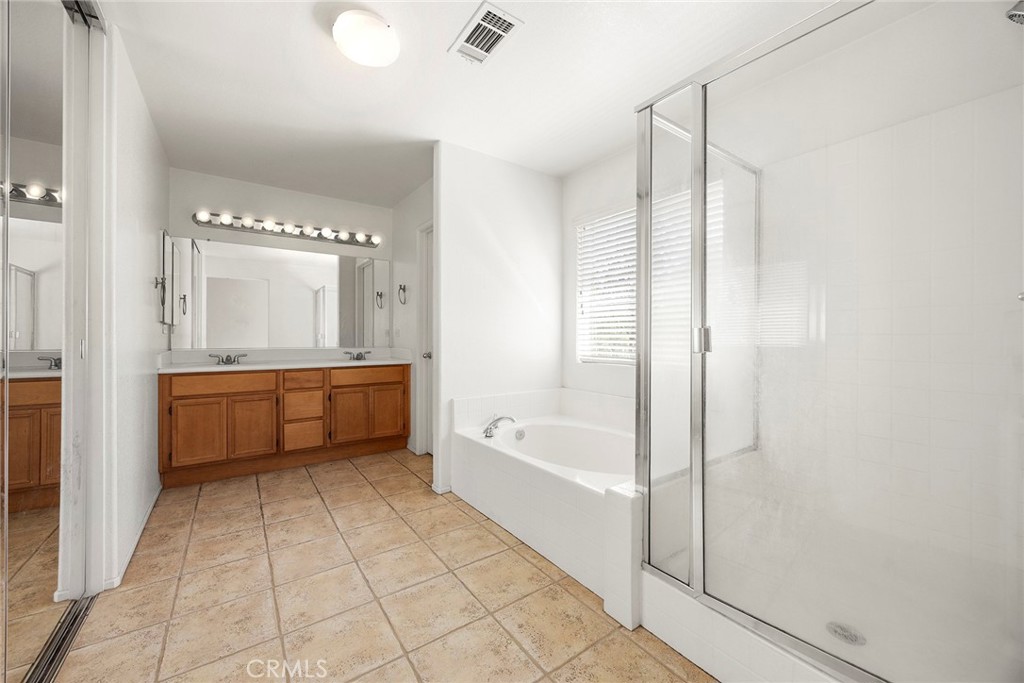 12351 Mesa Grove Drive Riverside, CA 92503 - Photo 15 of 32 a bathroom with a double vanity sink a mirror and a bathtub