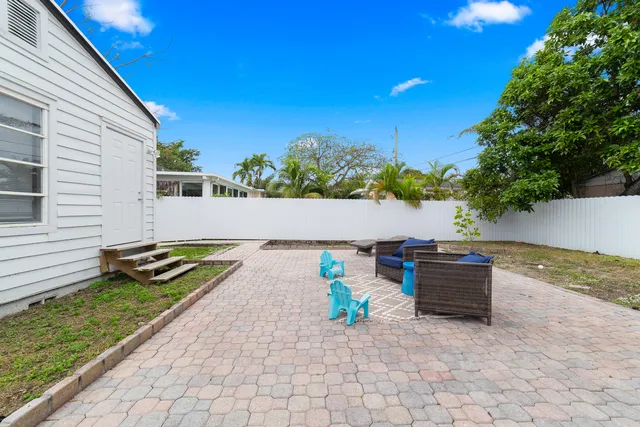 a view of a backyard with chairs and potted plants