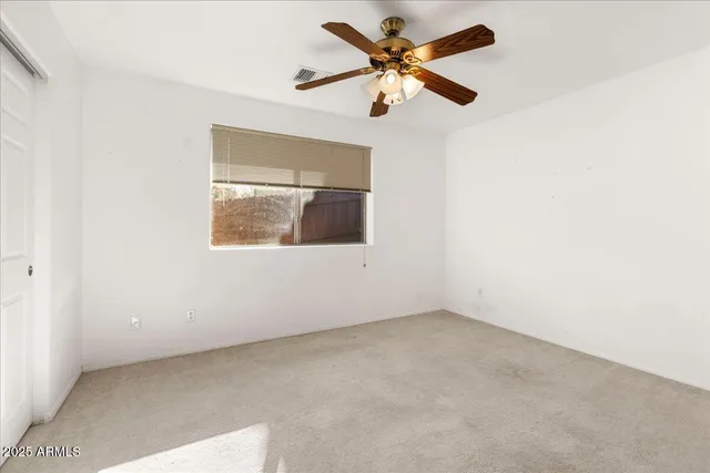 an empty room with a window and a fan