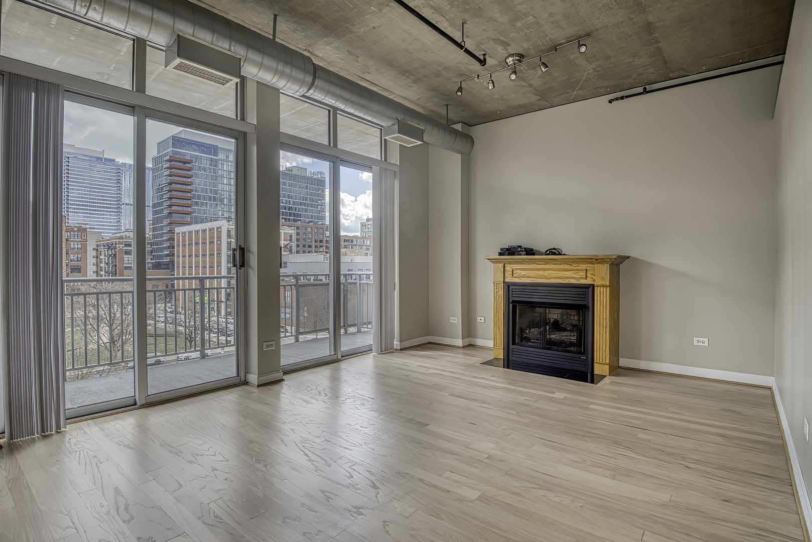 111 South Morgan Street, Unit 518 Chicago, IL 60607 - Photo 6 of 18 an empty room with wooden floor fireplace and windows