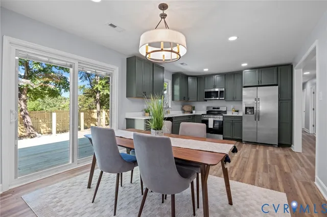 a kitchen with stainless steel appliances granite countertop a kitchen island hardwood floor sink stove dining table and chairs