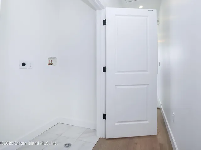 an empty room with a white wall and natural light