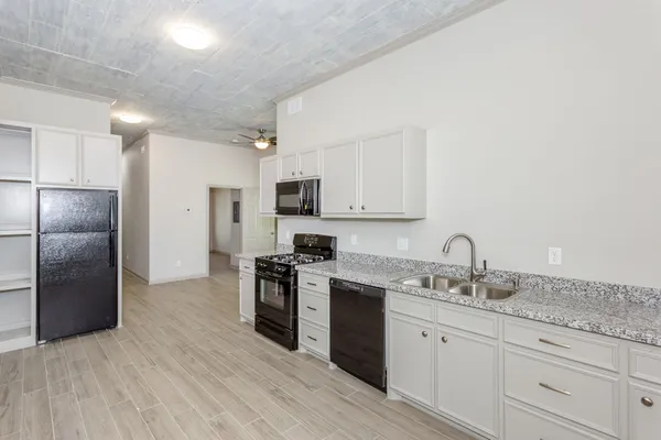 a kitchen with granite countertop a refrigerator stove and sink