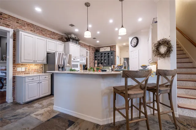 a kitchen with stainless steel appliances kitchen island granite countertop a table chairs and a refrigerator