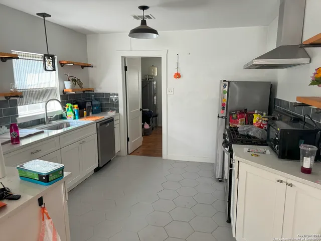 a kitchen that has a lot of white cabinets and stainless steel appliances