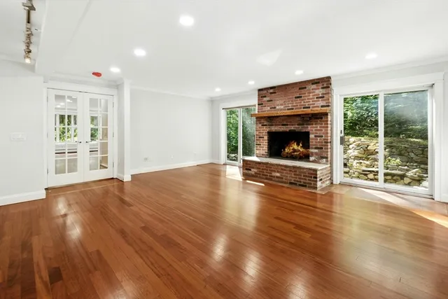 an empty room with wooden floor fireplace and windows