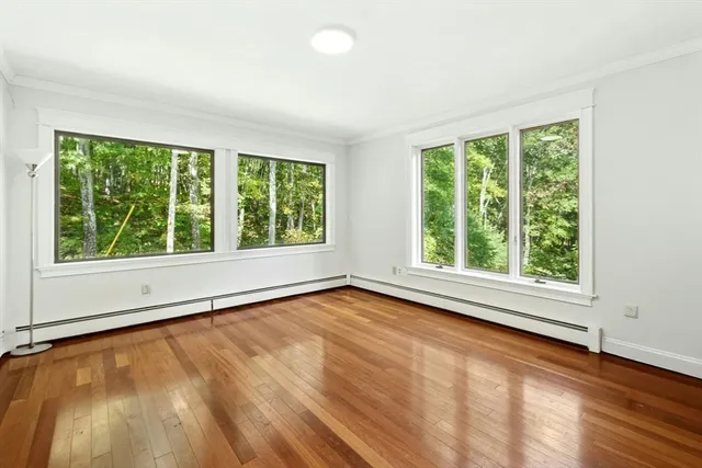 a view of an empty room with a window and wooden floor