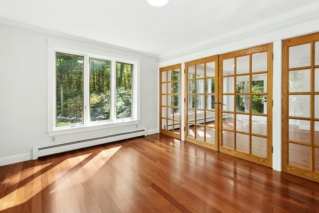 a view of an empty room with wooden floor and a window