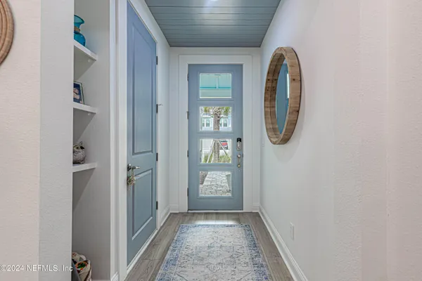 a view of a hallway with wooden floor and a bathroom