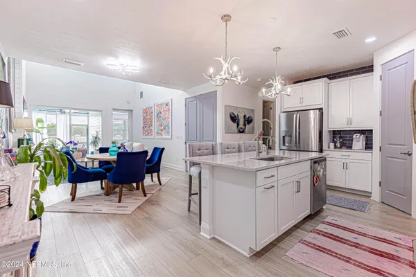 a kitchen with granite countertop a refrigerator a stove a dining table and chairs with wooden floor