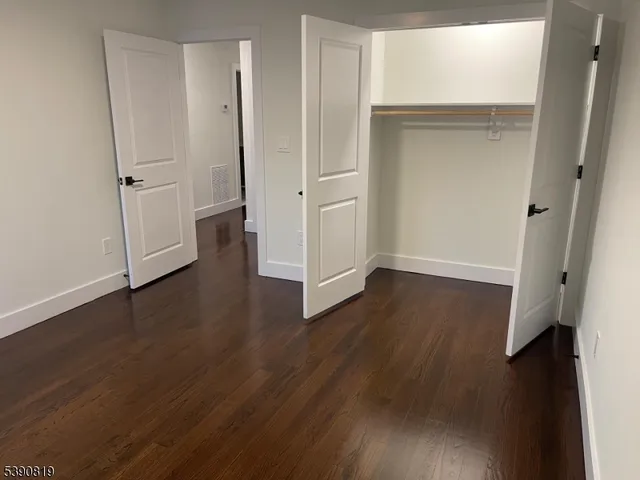 an empty room with wooden floor and entrance