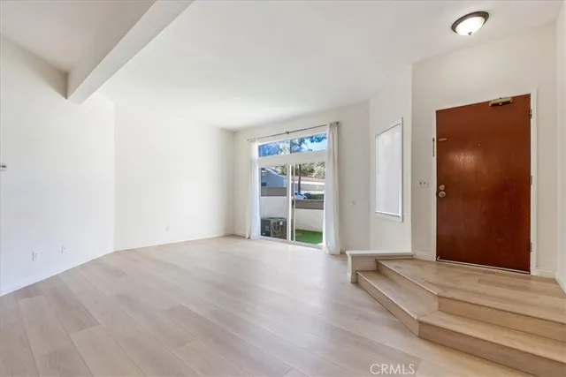 a view of an empty room with wooden floor and closet
