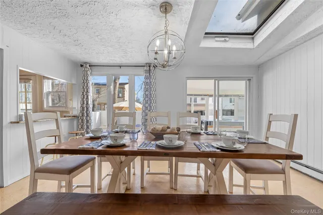 a dining room with wooden floor a chandelier a wooden table and chairs