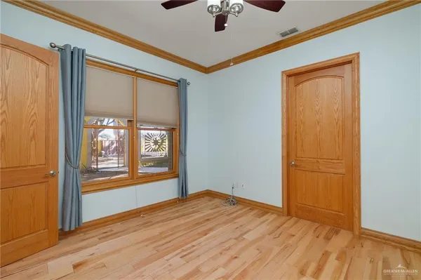 a view of empty room with wooden floor and fan