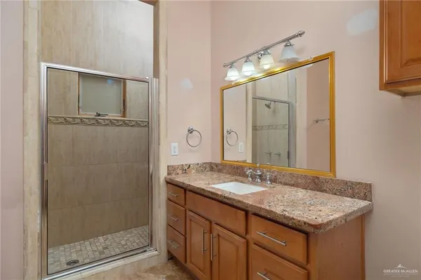 a bathroom with a granite countertop sink a mirror and a shower