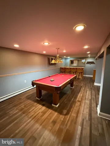 a room with wooden floor pool table and windows