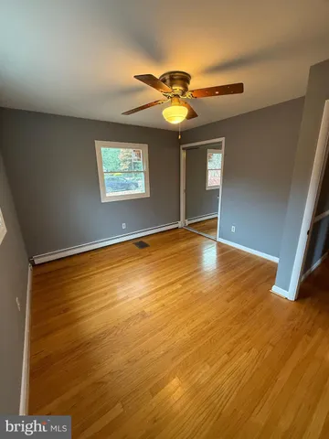 a view of an empty room with window and wooden floor
