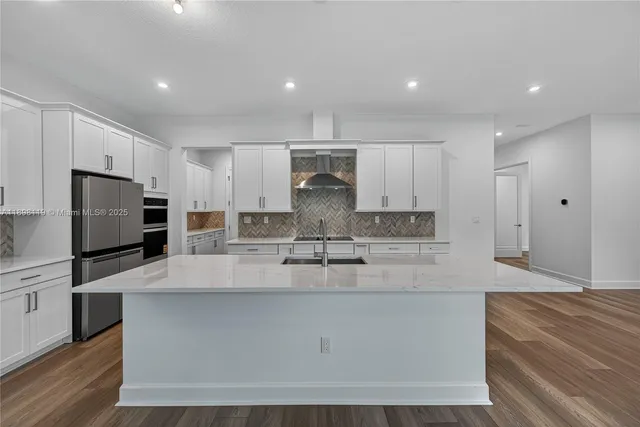 a large kitchen with kitchen island a large counter top stainless steel appliances and cabinets