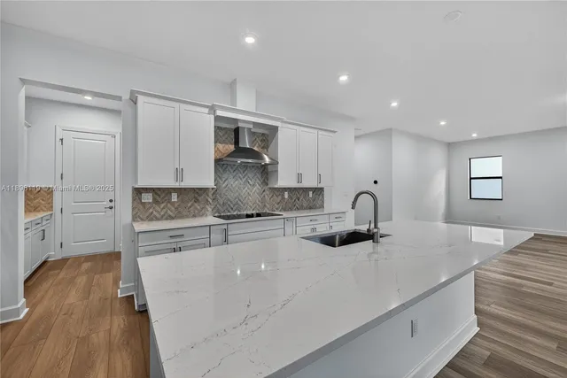 a kitchen with kitchen island granite countertop a sink cabinets and wooden floor
