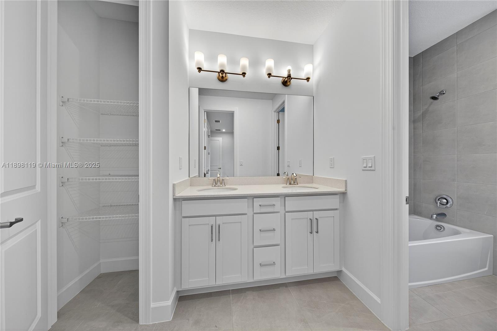 2722 Northwest 87th Terrace Cooper City, FL 33024 - Photo 26 of 44 a bathroom with a double vanity sink a large mirror a bathtub and