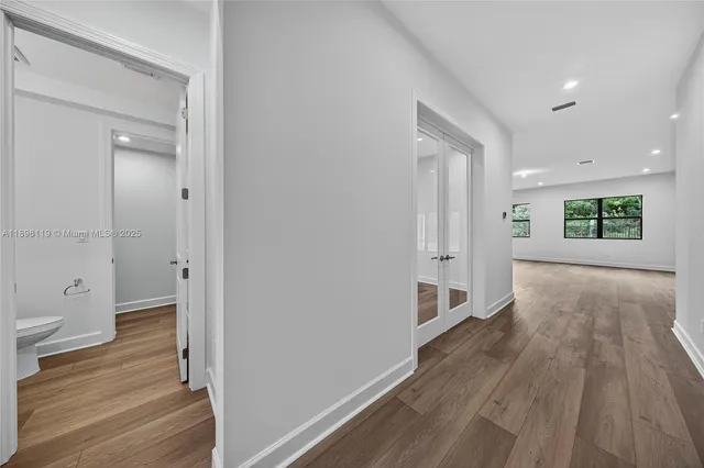 a view of a hallway with wooden floor and a bathroom