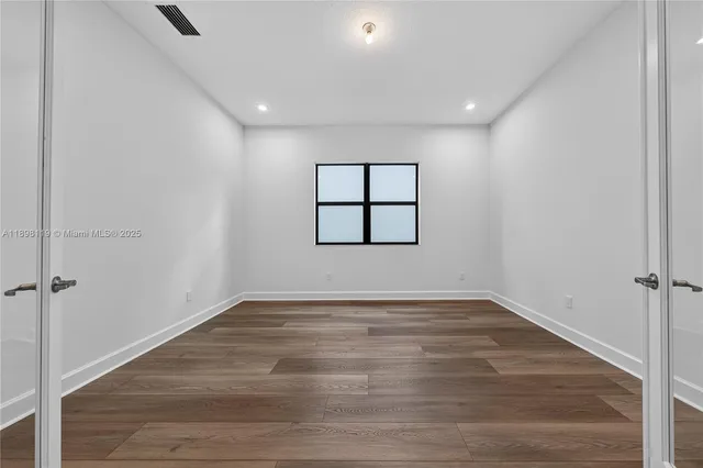 an empty room with wooden floor and window