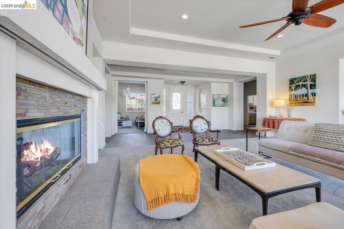 258 Rock Ridge Lane Copperopolis, CA 95228 - Photo 24 of 47 Living room featuring light tile patterned floors, a stone fireplace, a ceiling fan, a tray ceiling, and recessed lighting