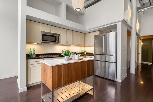 a kitchen with stainless steel appliances white cabinets and wooden floor