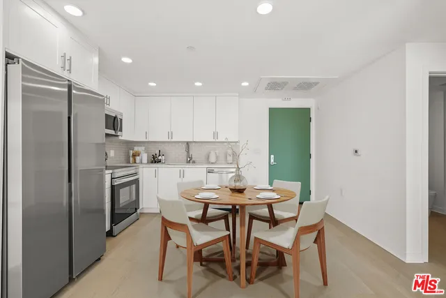 a kitchen with a refrigerator a dining table and chairs