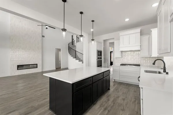 a kitchen with a sink a stove a refrigerator and white cabinets