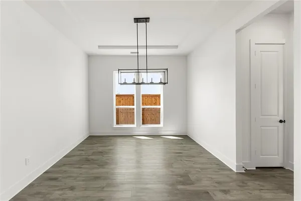 an empty room with wooden floor cabinet and windows