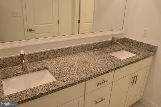 a bathroom with a granite countertop sink a mirror and shower