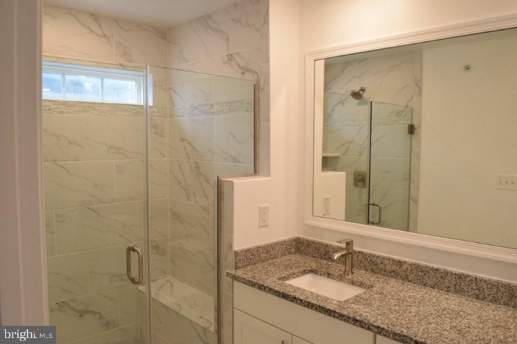 7505 Ledgers Way Hanover, MD 21076 - Photo 33 of 50 a bathroom with a granite countertop sink a mirror and shower
