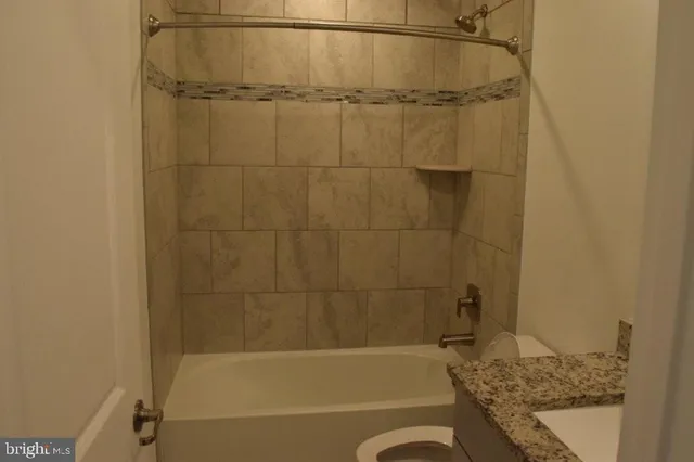 a bathroom with a granite countertop sink a toilet and bathtub