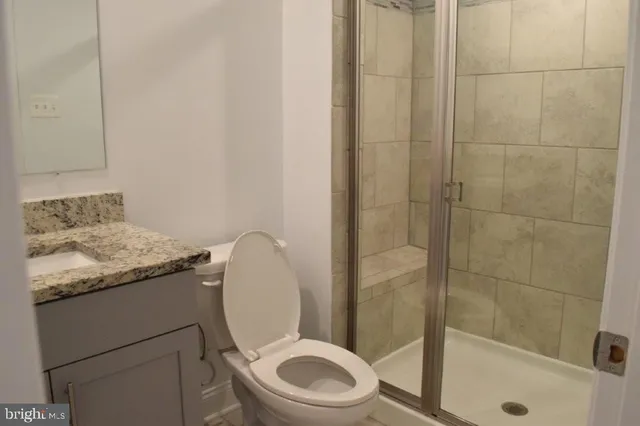 a bathroom with a granite countertop sink toilet and shower