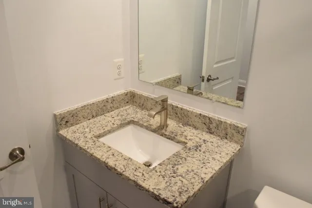 a bathroom with a granite countertop sink and a mirror