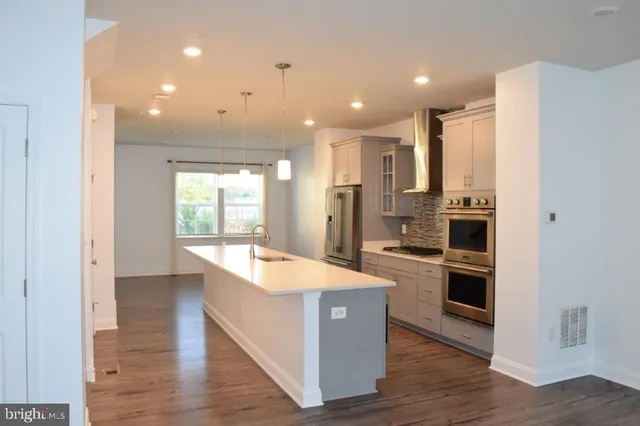 a large kitchen with a large counter top stainless steel appliances and wooden floor