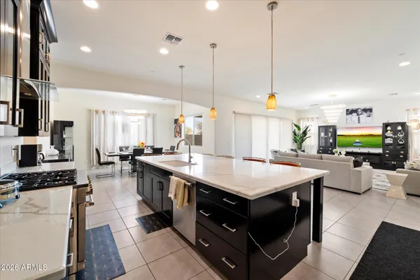 a kitchen with kitchen island a stove a sink a counter top space and living room view