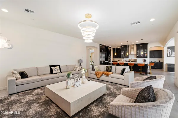 a living room with furniture kitchen view and a chandelier