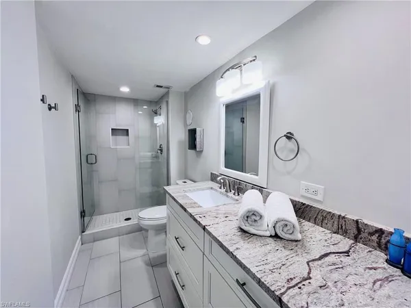 a bathroom with a granite countertop sink a toilet and shower